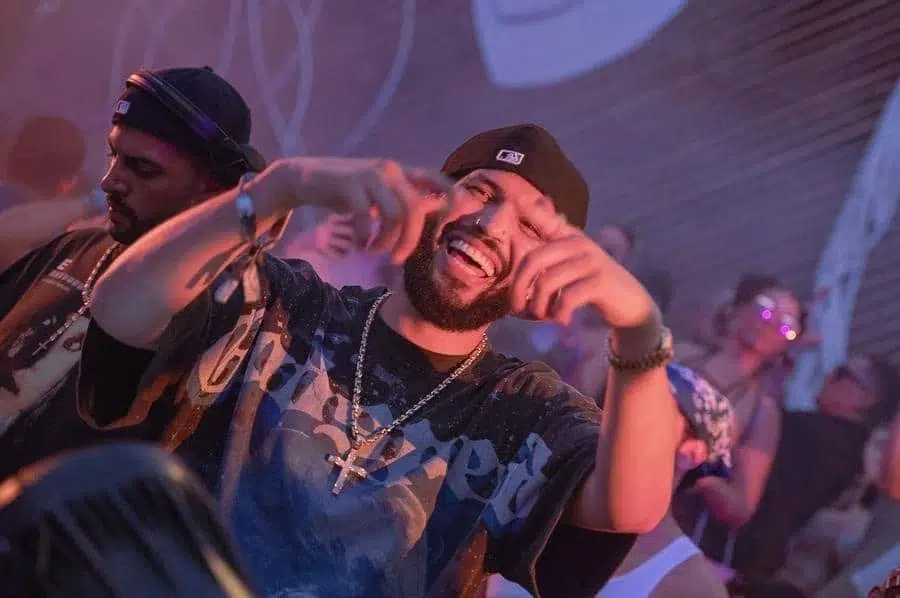 festivals in costa rica-38 | Pacific Photography Bearded man in a cap dancing and laughing at a crowded nightclub with colorful lights in the background.