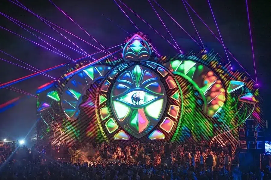 festivals in costa rica-39 | Pacific Photography Colorful illuminated festival stage with a large geometric eye emblem, neon panels, and laser beams over a cheering crowd at night.