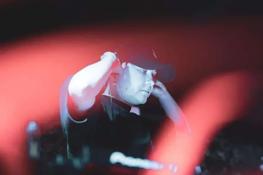 festivals in costa rica-67 | Pacific Photography DJ wearing a black cap adjusts headphones while performing, with red stage lights sweeping across the scene