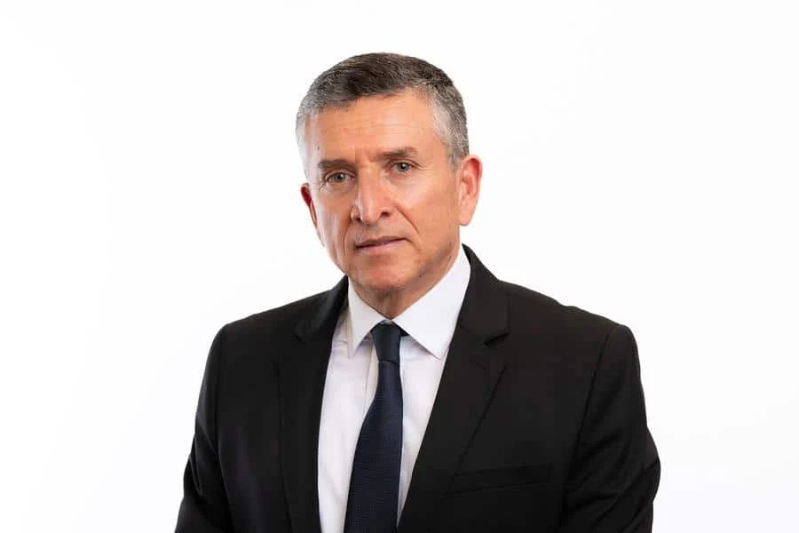 brands business and corporate photography -36 | Pacific Photography Portrait of a middle-aged man in a black suit and navy tie against a white background, looking at the camera.