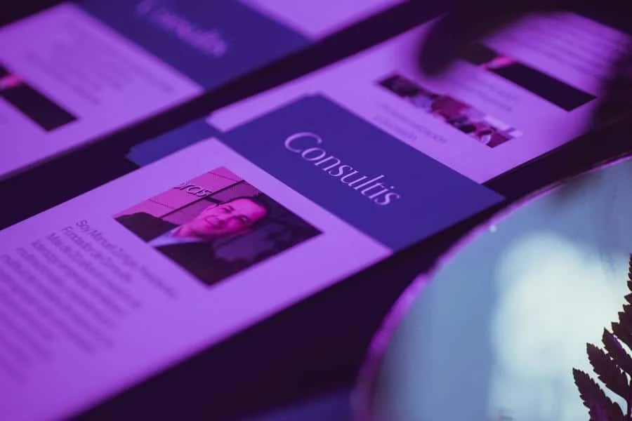 brands business and corporate photography -9 | Pacific Photography Close-up of glossy business cards under purple lighting, one card showing a portrait photo and the word 'Consultus'.
