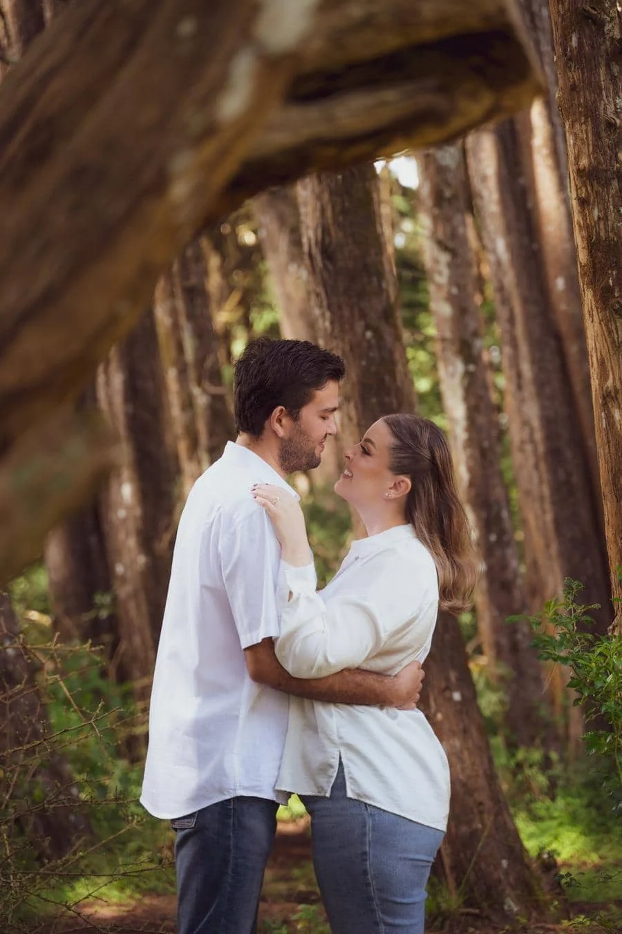 fotografía-de-compromiso-costa-rica-11 | Pacific Photography Pareja abrazándose en un sendero boscoso, compartiendo una sonrisa mientras se miran.