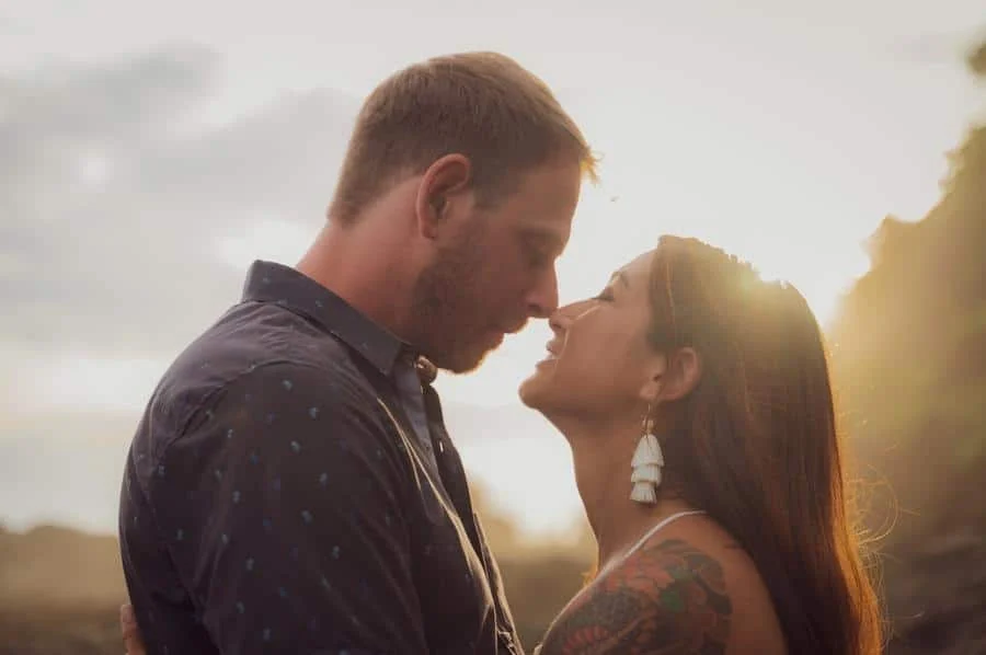 engagement photography costa rica-5 | Pacific Photography Couple kissing outdoors at sunset, embracing with warm backlight behind them.