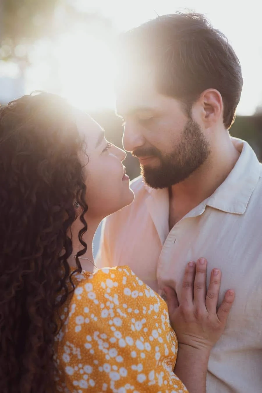 engagement photography costa rica-6 | Pacific Photography Close-up of a couple sharing an intimate moment outdoors, with warm backlight and the woman resting a hand on the man's chest.