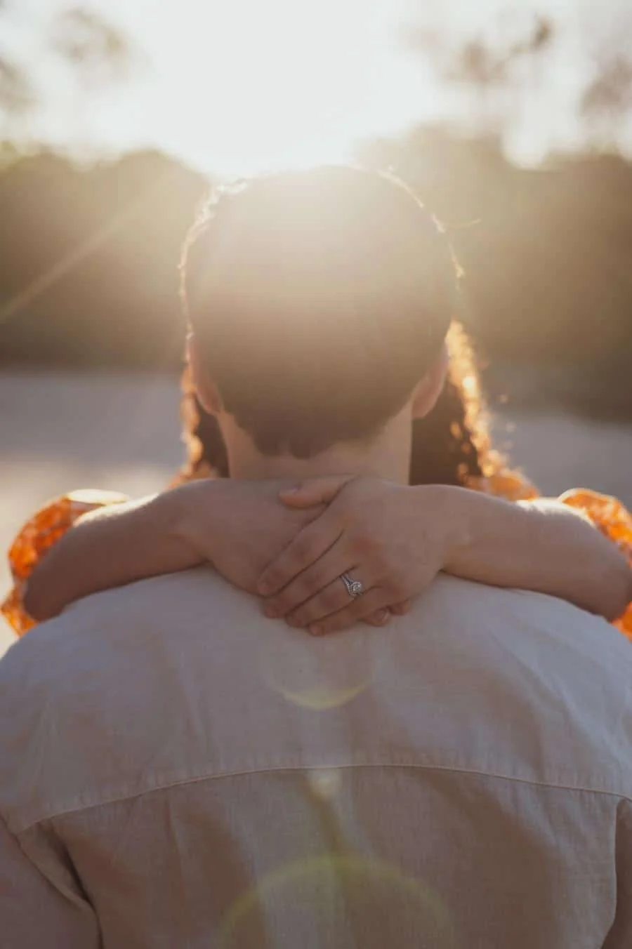 engagement photography costa rica-7 | Pacific Photography Couple embraces from behind at sunset; hands resting on each other’s shoulders, engagement ring visible on finger