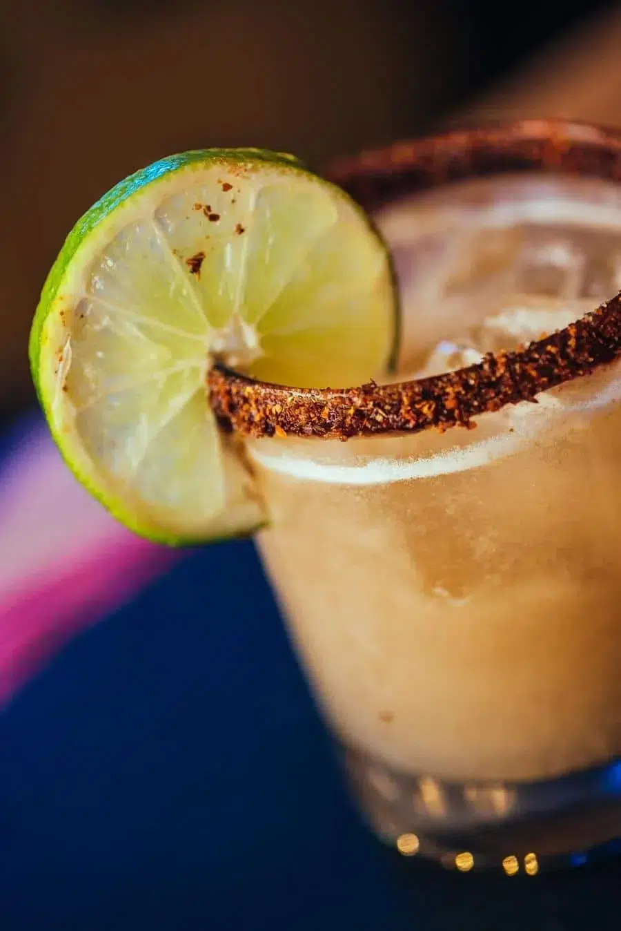 Close-up of a margarita in a salt-rimmed glass with a lime wedge garnish.
