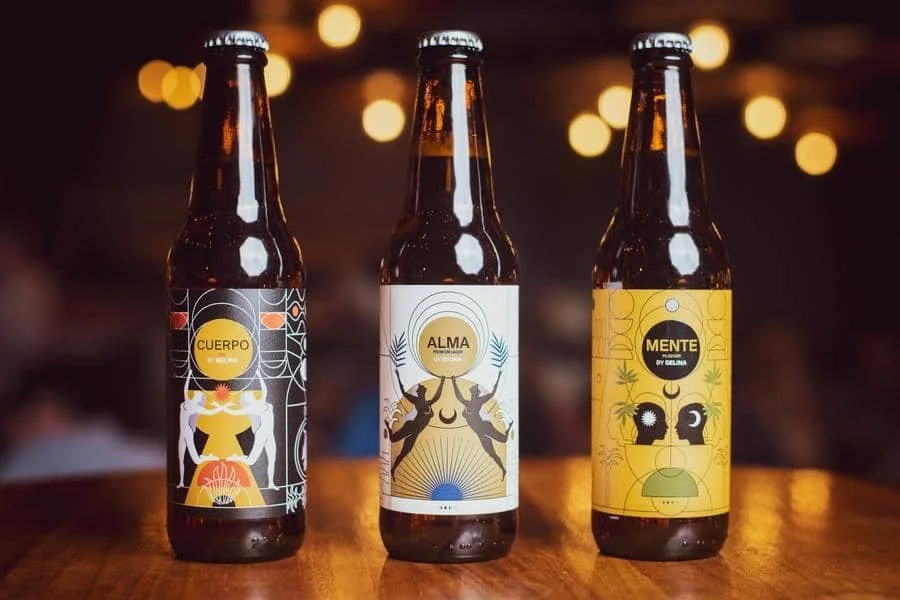 food menu and restaurant photography costa rica -27 | Pacific Photography Three craft beer bottles with decorative labels on a wooden table at a bar setting.