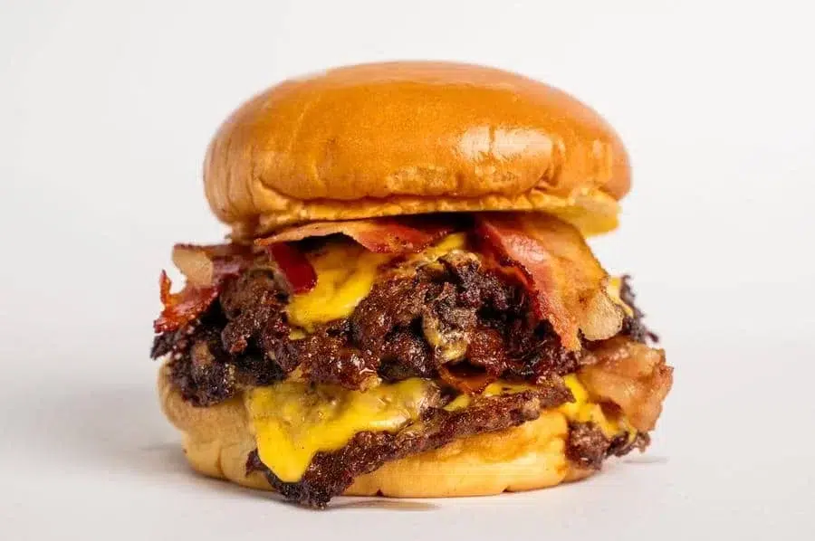 food menu and restaurant photography costa rica -30 | Pacific Photography Double cheeseburger with bacon and melted cheese on a soft bun against a white background.