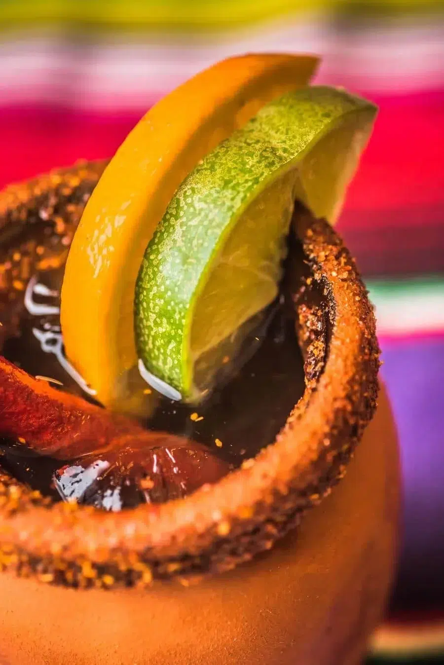 Close-up of a salted-rim cocktail with lime and lemon wedges as garnish.