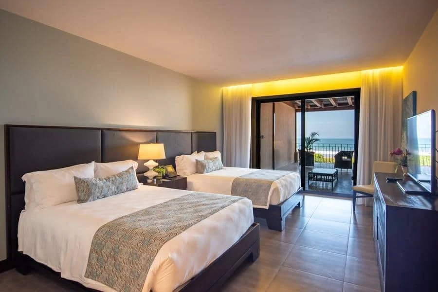 fotografia-para-propiedades-espacios-4 | Pacific Photography Habitación de hotel con dos camas queen y un balcón con vista al océano.