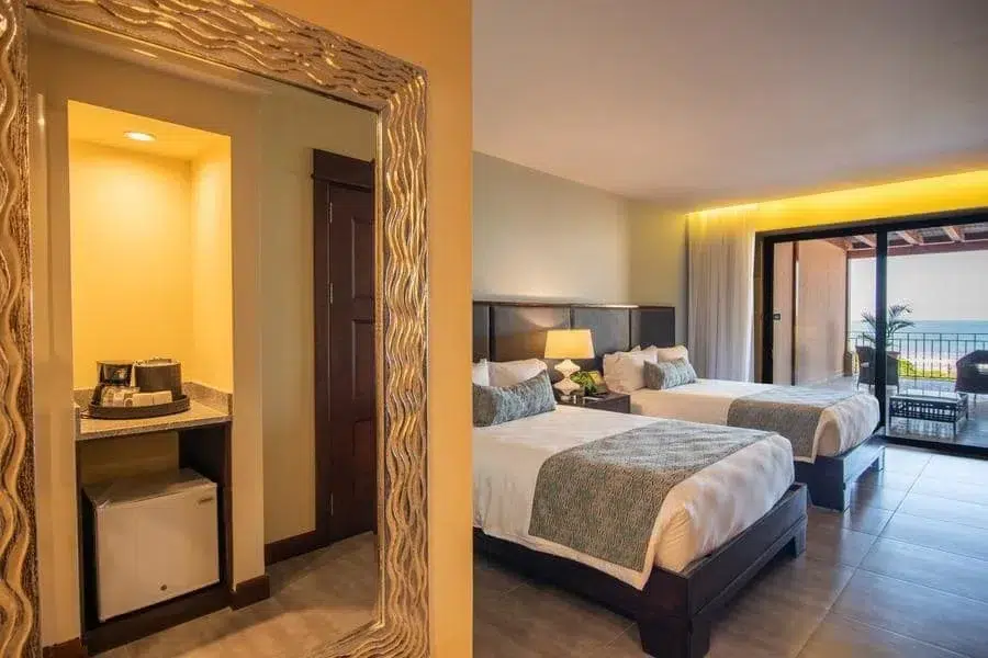 fotografia-para-propiedades-espacios-5 | Pacific Photography Habitación de hotel con dos camas dobles, una lámpara de noche y un balcón con vista al mar.