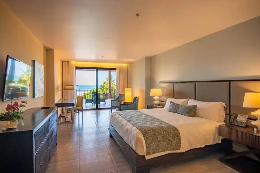 fotografia-para-propiedades-espacios-7 | Pacific Photography Habitación de hotel con una cama king, mesitas de noche y un balcón con vista al mar.