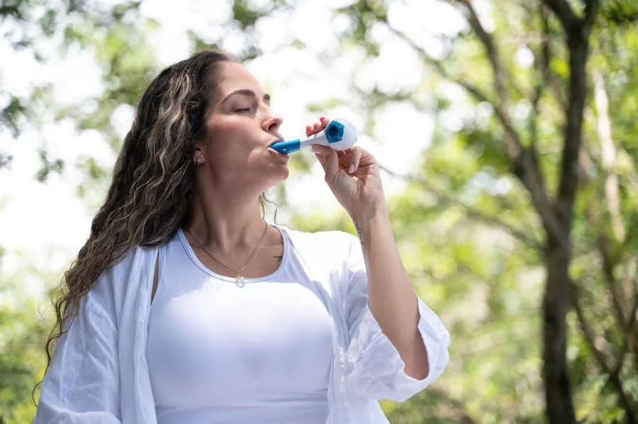 product photography costa rica -15 | Pacific Photography Woman standing in a sunny park blowing bubbles with a blue bubble wand.