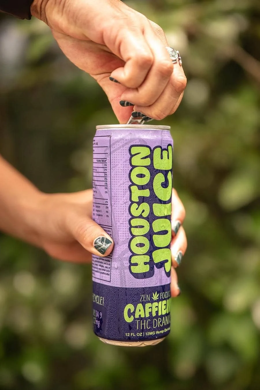 product photography costa rica -3 | Pacific Photography Close-up of a hand opening a purple can labeled caffeine THC drink outdoors, nails painted dark.