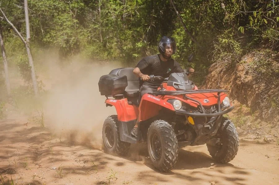 sports and adventure photography costa rica -10 | Pacific Photography Man riding a red ATV on a dusty forest trail, wearing a helmet and protective gear.
