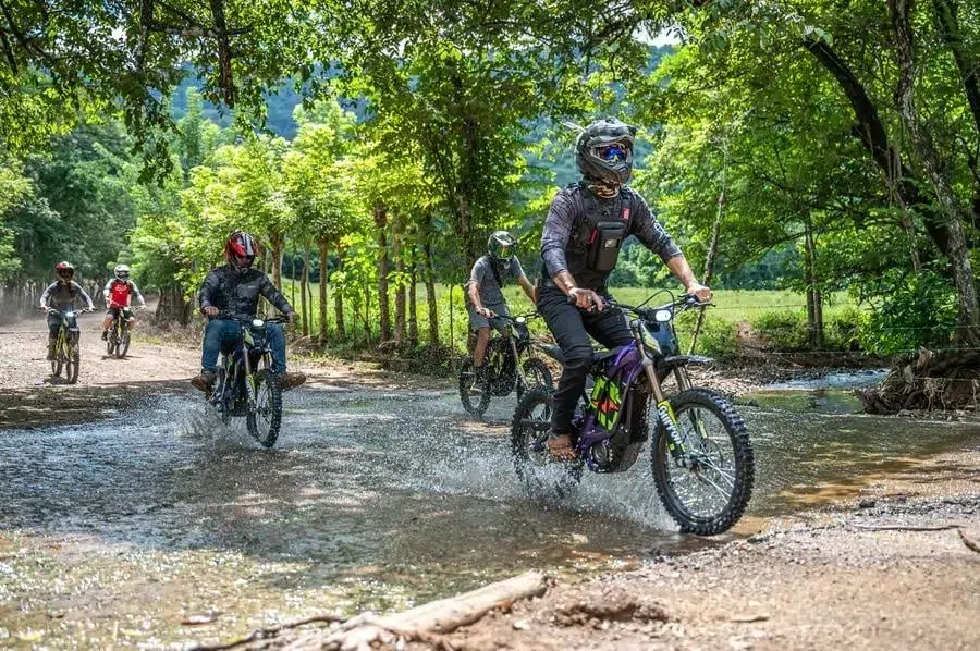 sports and adventure photography costa rica -16 | Pacific Photography Group of riders wearing helmets cross a shallow river on a forest dirt trail.
