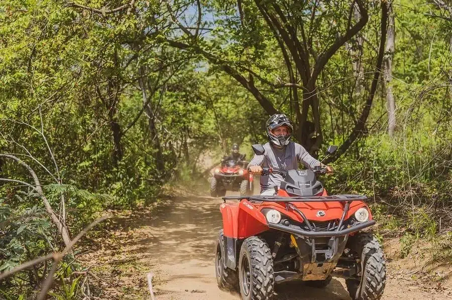 sports and adventure photography costa rica -9 | Pacific Photography Person wearing helmet riding a red ATV along a dirt forest trail, with another rider in the background.