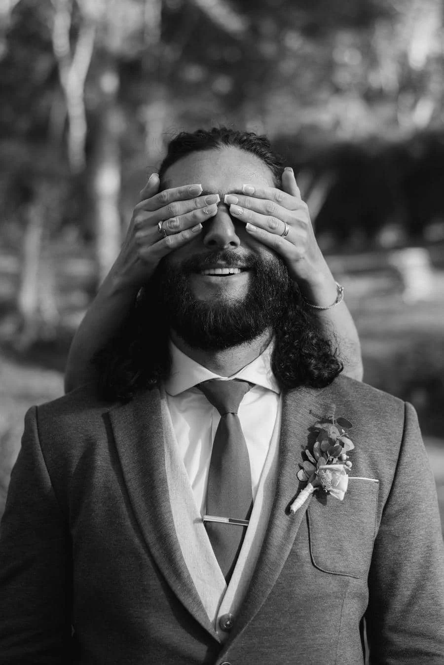 wedding ceremony photography costa rica-3 | Pacific Photography Groom in a suit with a boutonniere smiles as someone covers his eyes playfully from behind.