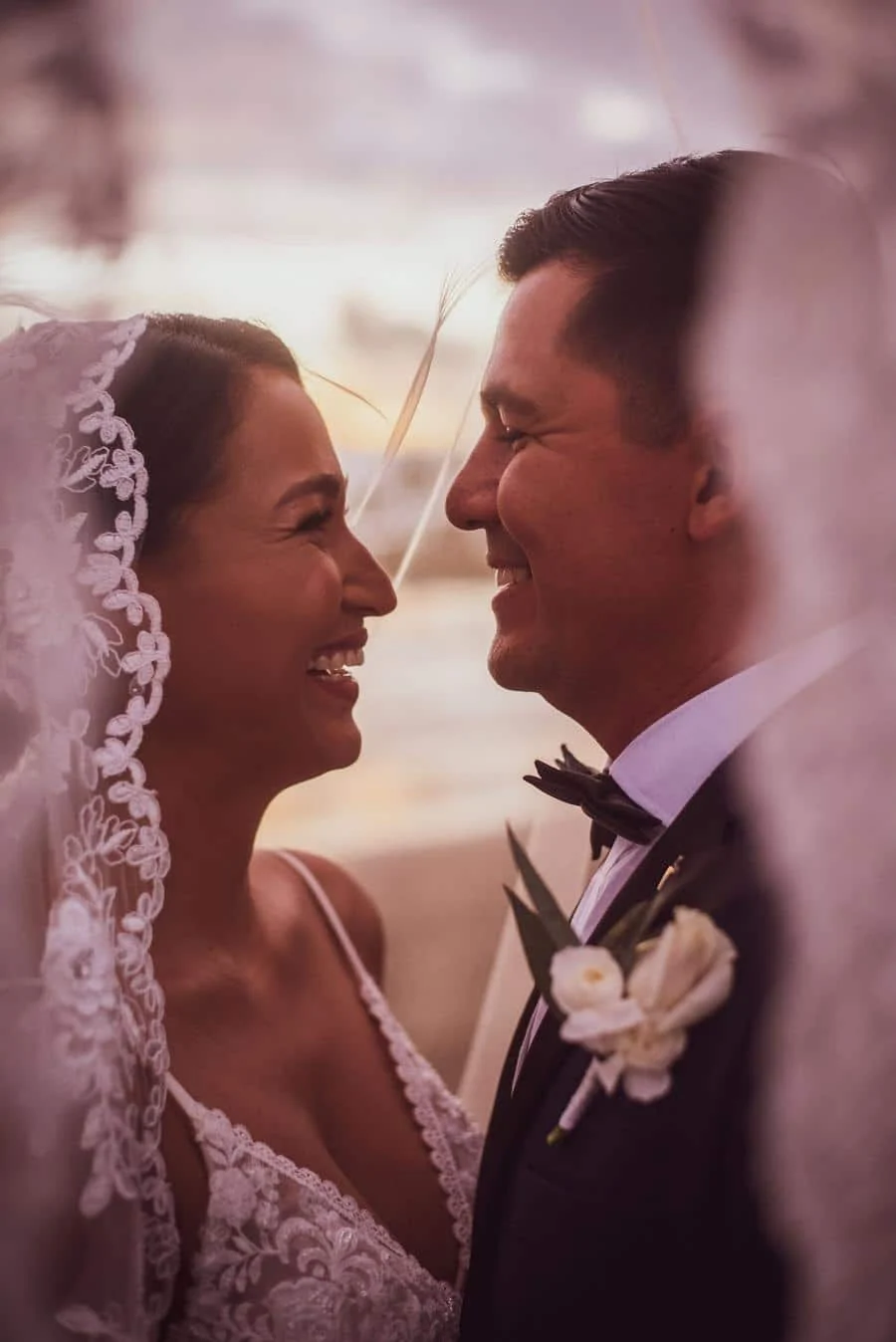 wedding ceremony photography costa rica-6 | Pacific Photography Bride and groom facing each other and smiling, bride wearing lace veil and gown, groom in a tux with a boutonniere, intimate wedding moment.