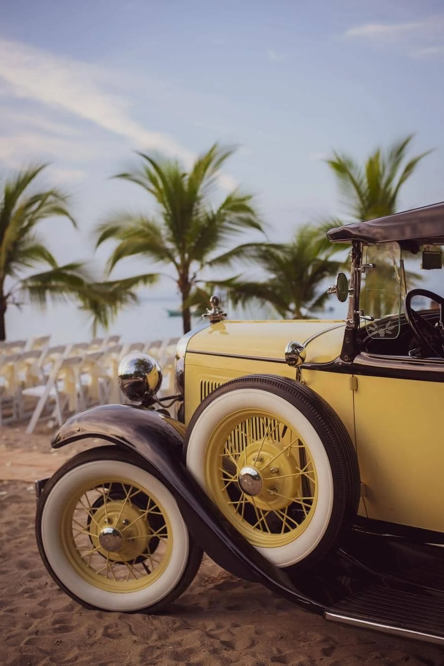 wedding ceremony photography costa rica-8 | Pacific Photography Vintage yellow convertible with white-wall tires parked on a sandy beach, palm trees in the background.