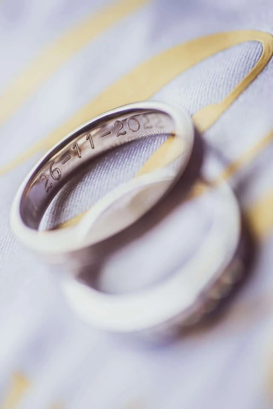 wedding prep photography costa rica-1 | Pacific Photography Close-up of a silver wedding ring with engraved date 26-11-2021 resting on patterned fabric.