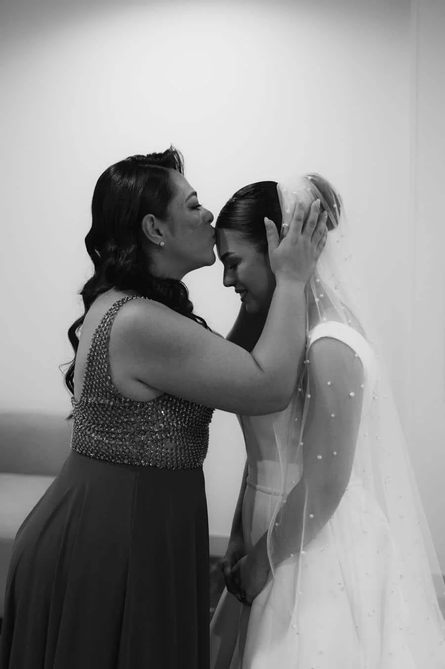 wedding prep photography costa rica-13 | Pacific Photography Mother of the bride in a sparkly gown kisses the bride on the forehead as she adjusts the veil.