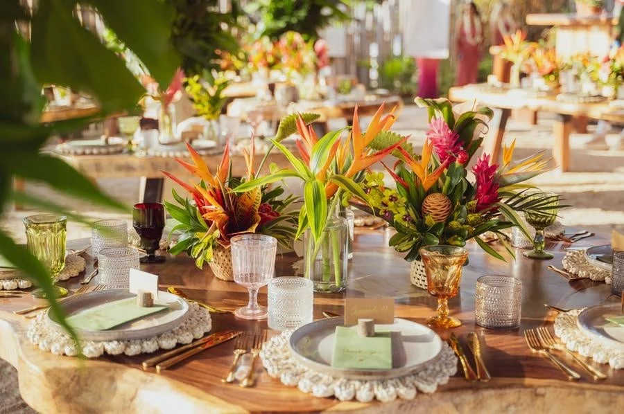 wedding reception and party photography in costa rica -5 | Pacific Photography Outdoor dining table with a tropical flower centerpiece, glassware, and elegant place settings on a wooden table in natural light.