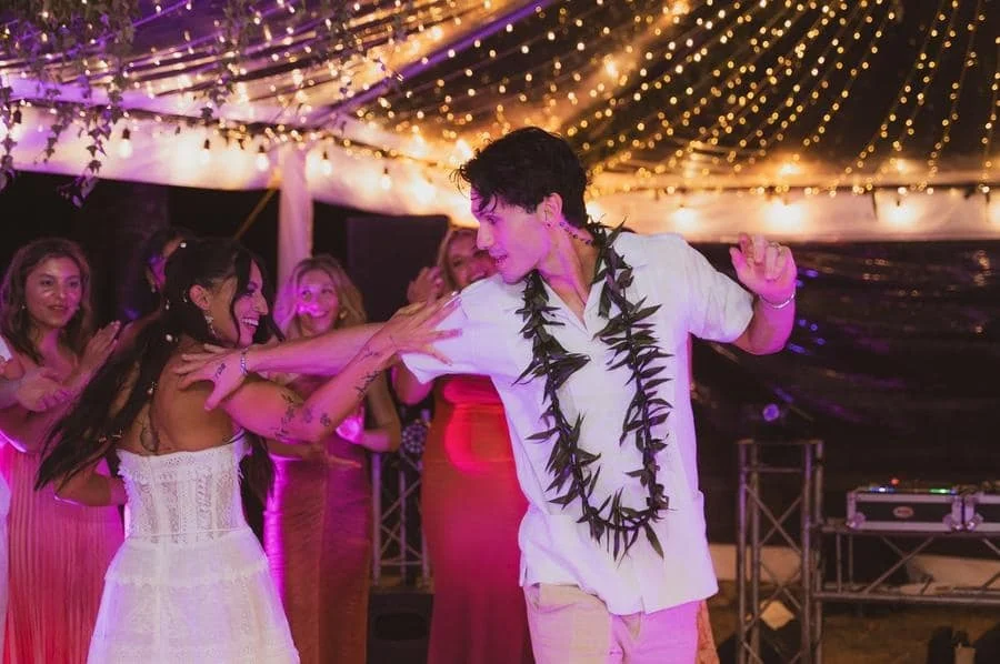 wedding reception and party photography in costa rica -9 | Pacific Photography Couple dancing at a festive party under twinkling string lights, with cheering guests around them.